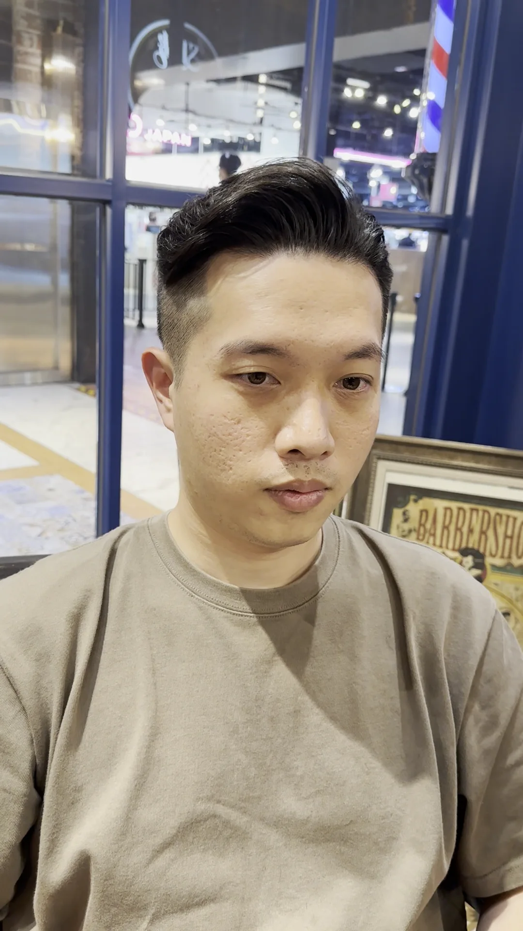 剪完後站在店門口的正面，頭髮往後帶出層次，背後是理髮店的三色燈柱與招牌